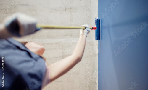 Decorator painter hand painting blue color wall with roller
