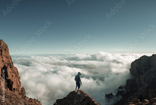 Man standing on the mountain peak above the clouds