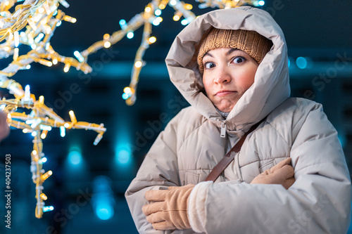 Photos Young woman in a warm down jacket and thermal underwear is frozen and shivering