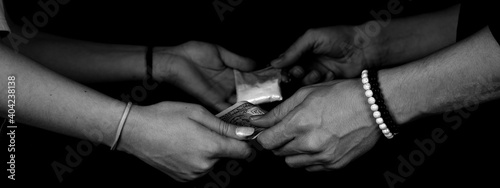 Hand of addict woman with buying dose of cocaine from drug dealer. Narcotics concept. Dramatic monochrome, black and white photo. Panoramic shot. Panorama banner. Close-up macro shot.