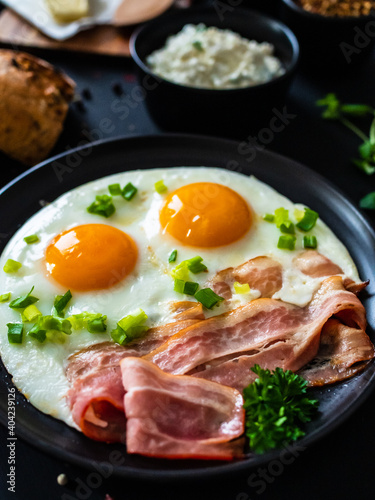 Continental breakfast - sunny side up eggs on bacon on wooden table