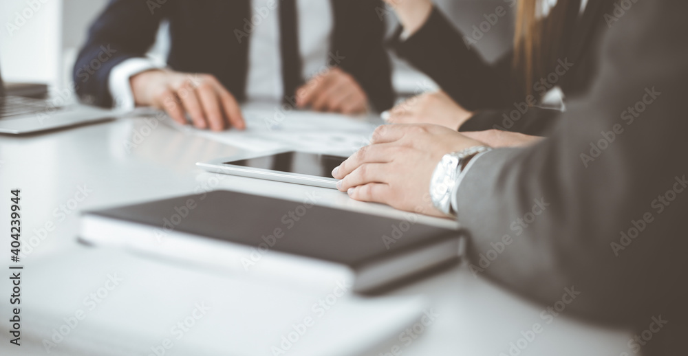 Unknown businessmen and woman sitting, working and discussing questions at meeting in modern office, close-up Unknown businessmen and woman sitting, working and discussing questions at meeting in modern office, close-up