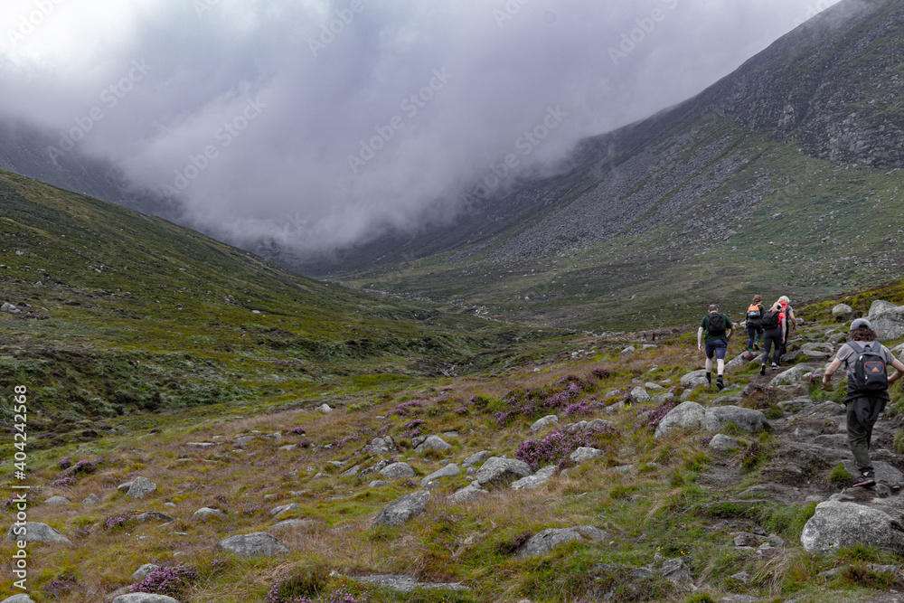 Tourists on a hike walking on turistic trail in the mountains of Northen Ireland.