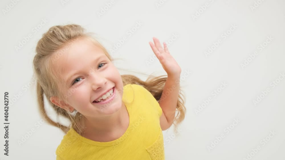 The girl is having fun and dancing on a white background in the studio in a yellow T-shirt. The girl is having fun and dancing on a white background in the studio in a yellow T-shirt.