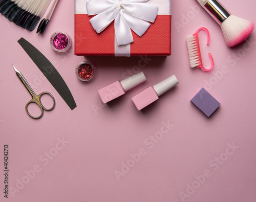 Set of manicure tools and accessories with red gift box on a pink background. Hardware manicure,Flat lay.