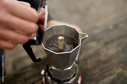 Traveler man making camping coffee outdoor with metal geyser coffee maker on a gas burner, step by step