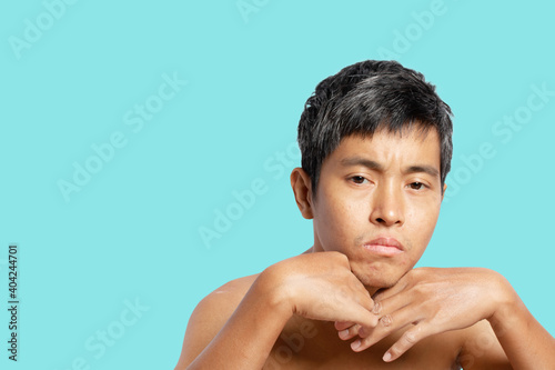 thoughtful young man something, a man takes off his shirt. on blue background.