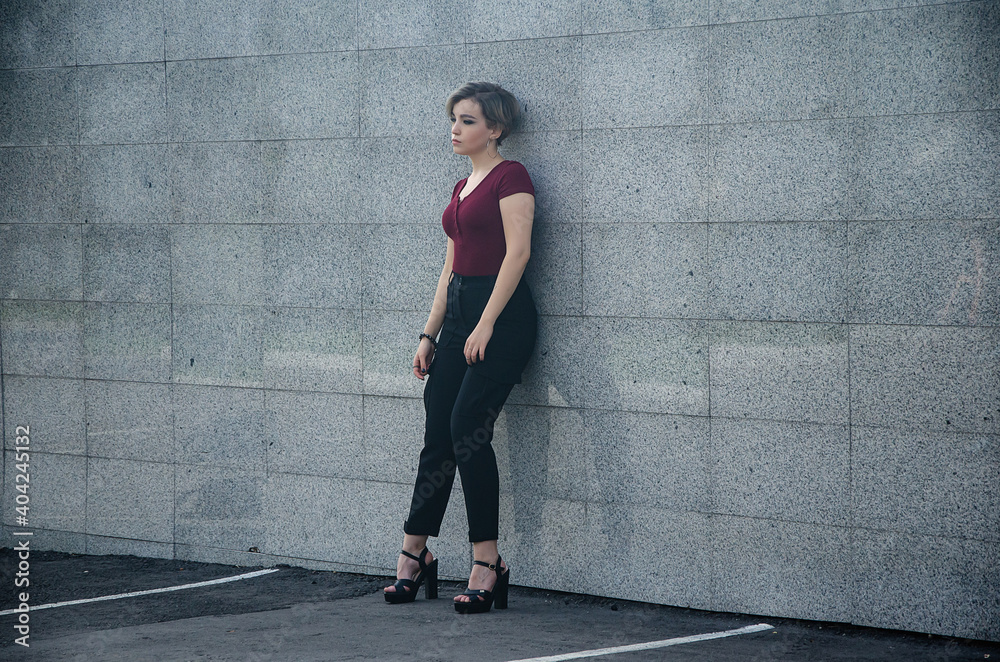 A girl stands on the street against a background of brick tiles A girl stands on the street against a background of brick tiles