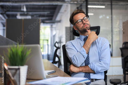 Focused businessman thinking at modern office into report file calculating stock market earnings, startup business.