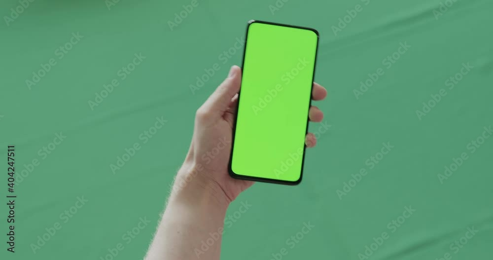 Man hand show phone with green screen over green background