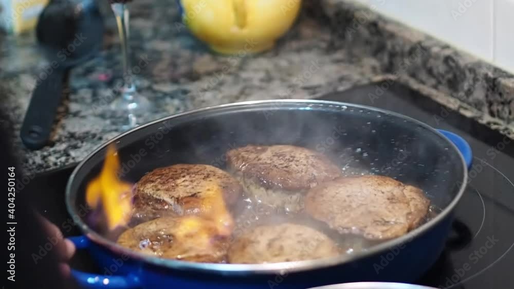 Chef flambéing beef tenderloins in a pan. Steaks with fire in kitchen with induction hob. Chef flambéing beef tenderloins in a pan. Steaks with fire in kitchen with induction hob.