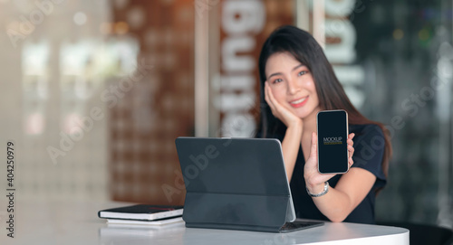 Portrait of female office worker presenting mock up smartphone screen.