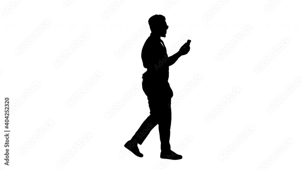 Silhouette Smiling African American businessman making video call holding mobile phone in his hand while walking. Silhouette Smiling African American businessman making video call holding mobile phone in his hand while walking.