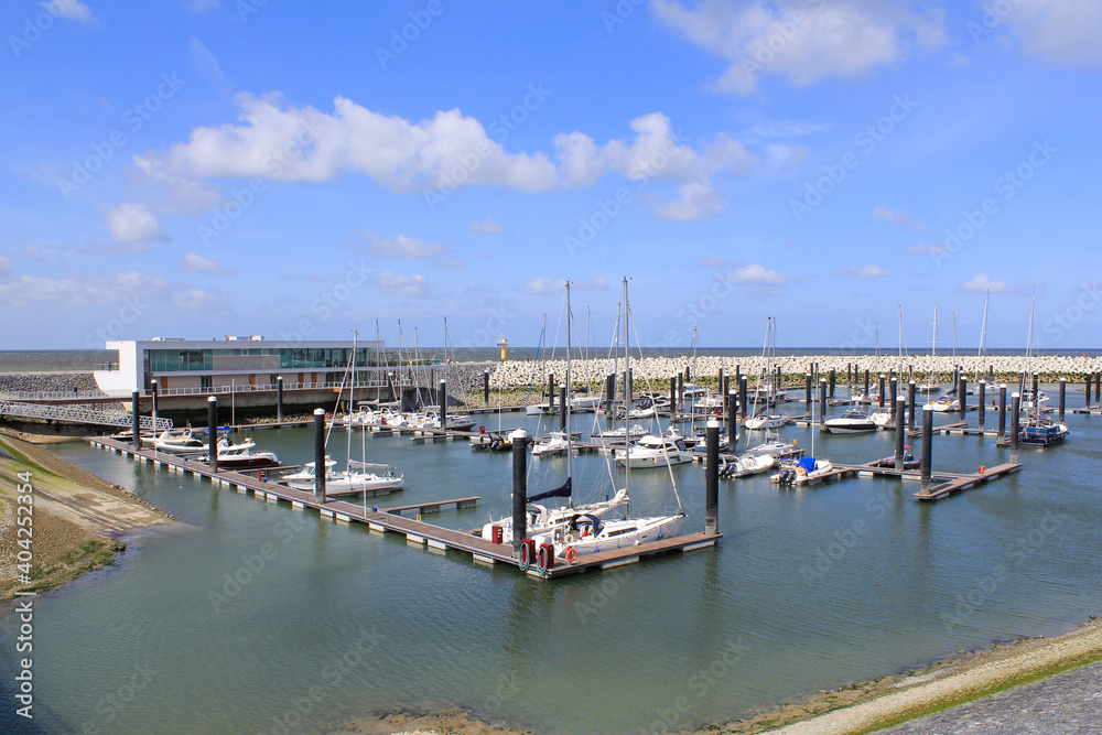 the marina with yachts and fishing boats and a restaurant at the dutch coast in Cadzand, zeeland in summer with a beautiful blue sky