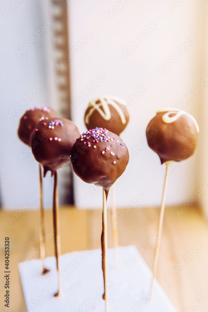 Chocolate covered bites also known as cake pops. Small glazed cakes on wood stick. Selective focus with room for text on white background. Chocolate covered bites also known as cake pops. Small glazed cakes on wood stick. Selective focus with room for text on white background.