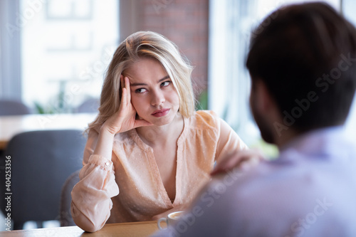 Young Caucasian woman disinterested in blind date, feeling bored with conversation at city cafe photo