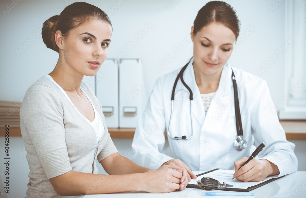 Doctor and patient are sitting and discussing health examination results in clinic office. Health care, medicine and good news concepts Doctor and patient are sitting and discussing health examination results in clinic office. Health care, medicine and good news concepts