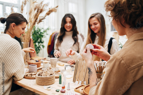 Four social friendly young women in an ecological shop picking and discussing various cosmetic. Standing in front of the table with variety of items. All are blurred exept one in a foreground.