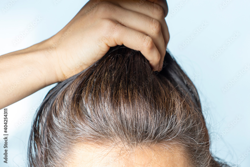 Obraz premium Head of middle age caucasian woman with black gray hair roots. Close up