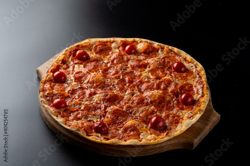 Hot oven-made pepperoni pizza with ,melted mozzarella cheese on smooth black background