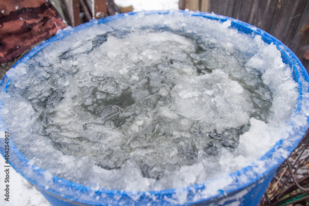 blue barrel in the garden with frozen ice with icicles