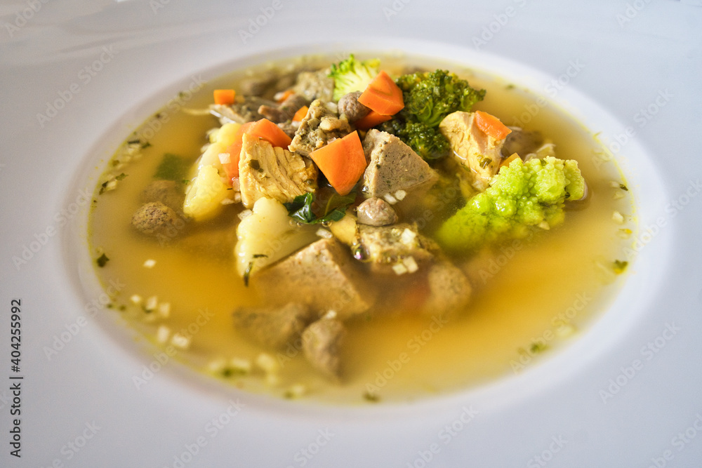 Ein weißer Teller Gemüsesuppe, Hühnersuppe mit Karotten, Leberknödel und Bio Gemüse, Hausrezept nach Oma in der Erkältungszeit Ein weißer Teller Gemüsesuppe, Hühnersuppe mit Karotten, Leberknödel und Bio Gemüse, Hausrezept nach Oma in der Erkältungszeit