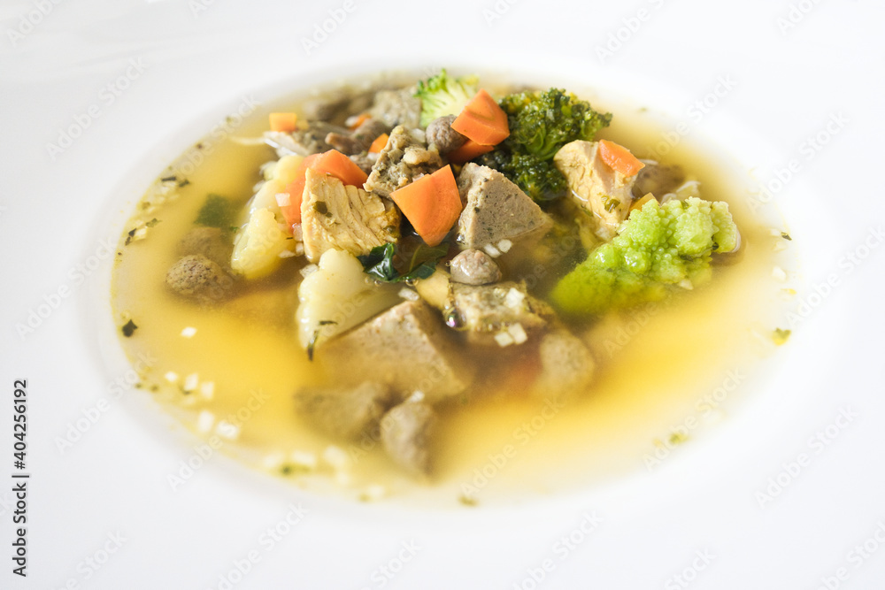 Ein weißer Teller Gemüsesuppe, Hühnersuppe mit Karotten, Leberknödel und Bio Gemüse, Hausrezept nach Oma in der Erkältungszeit