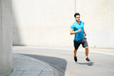 Young man running on the street during sunny summer weather