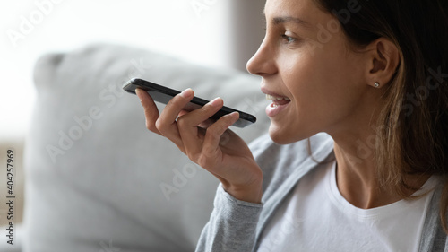 Foto Close up smiling woman recording voice message, holding phone near mouth, sittin