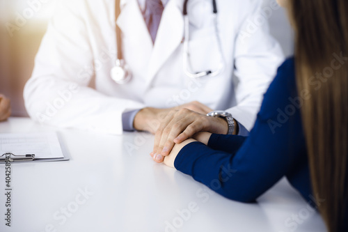 Unknown man-doctor reassuring his female patient  close-up. Two physicians consulting and giving some advices to woman. Concepts of medical ethics and trust. Empathy in medicine