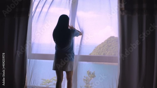 4K Camera moving follow rear back view happy travel women with  suitcase opening curtain lace standing in luxury villa hotel and looking through window enjoy with tropical sea view. Holiday travel