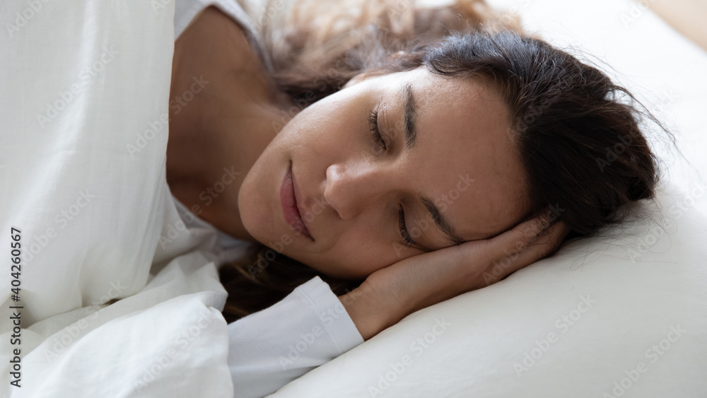 Close up peaceful beautiful woman sleeping with hand under cheek in comfortable bed, calm young female with closed eyes resting on soft pillow, enjoying fresh white bedclothes, refreshment Close up peaceful beautiful woman sleeping with hand under cheek in comfortable bed, calm young female with closed eyes resting on soft pillow, enjoying fresh white bedclothes, refreshment