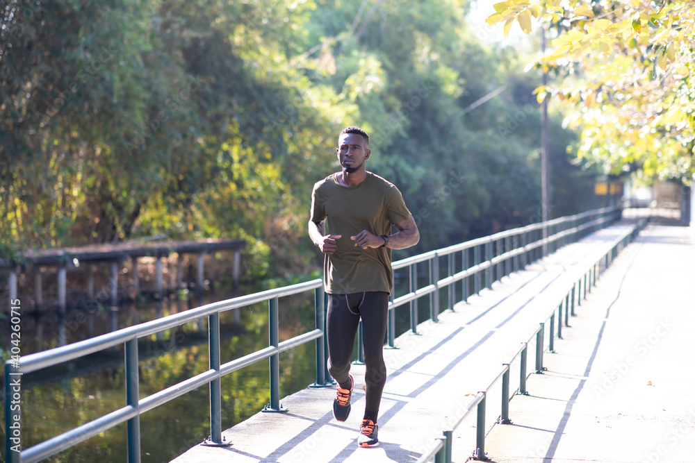 Black Man jogging and running beside road in park at autumn morning. Black Man jogging and running beside road in park at autumn morning.