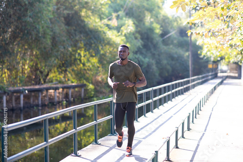 Black Man jogging and running beside road in park at autumn morning.