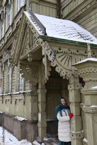 Porch door of wooden house with ornamental windows, carved frames of merchant Sapozhnikov on Simanovsky Street, 14 (Sverdlova, 63), Kostroma city, Russia. Russian style in architecture. Tourist girl photo