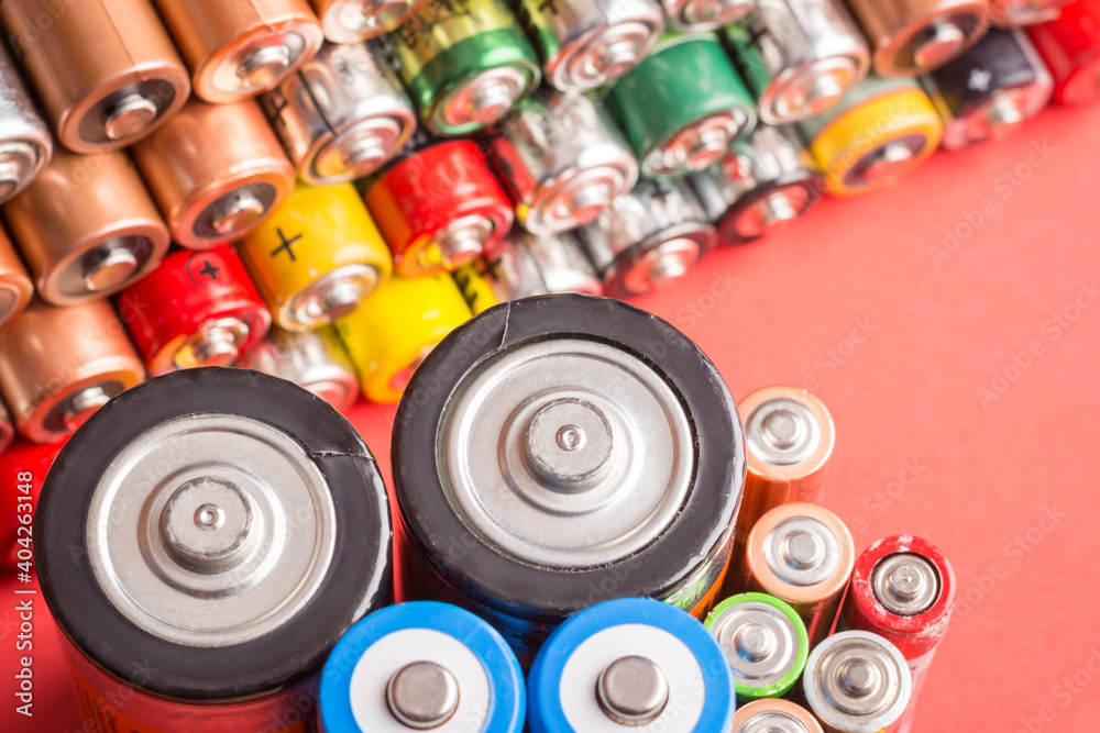 Stack of used batteries on a red background. Concept of power Stack of used batteries on a red background. Concept of power