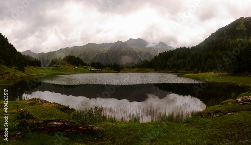 mountain lake with houses and dense rain clouds panorama