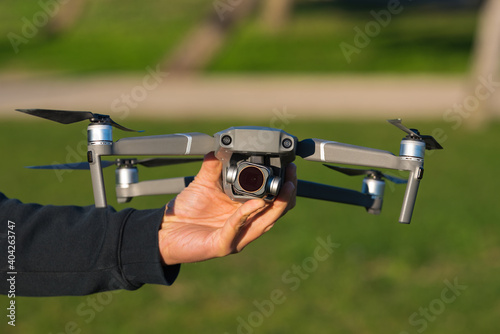 Man holding grey drone outside in the park. Ready for flight