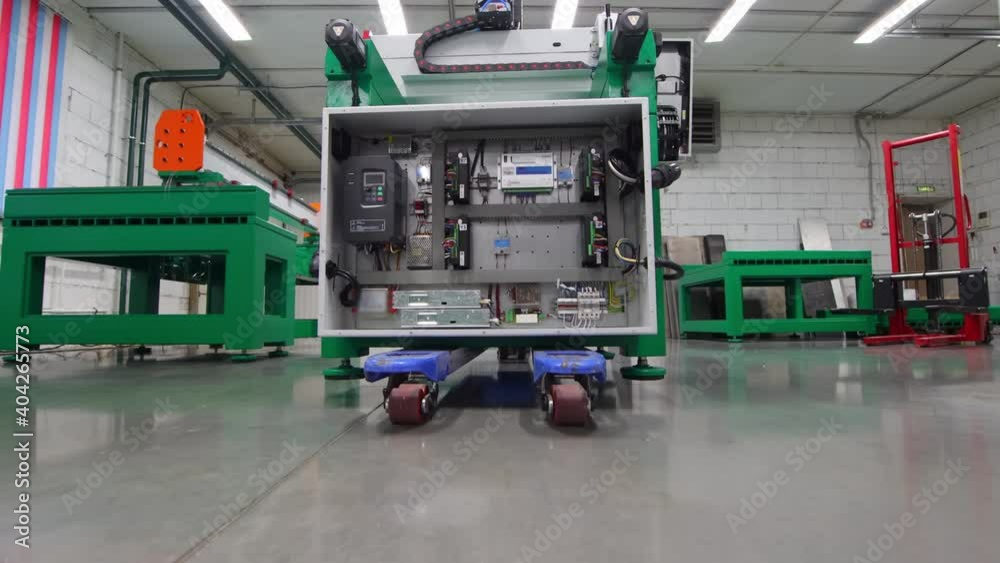 A man worker rolls a trolley with a block with wires inside through an industrial warehouse A man worker rolls a trolley with a block with wires inside through an industrial warehouse