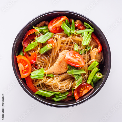 delicious glass noodles with chicken and vegetables on a white acrylic background