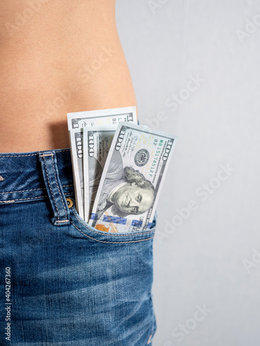 100 bills stick out of the front pocket of his jeans The concept of money in your pocket. vertical photo