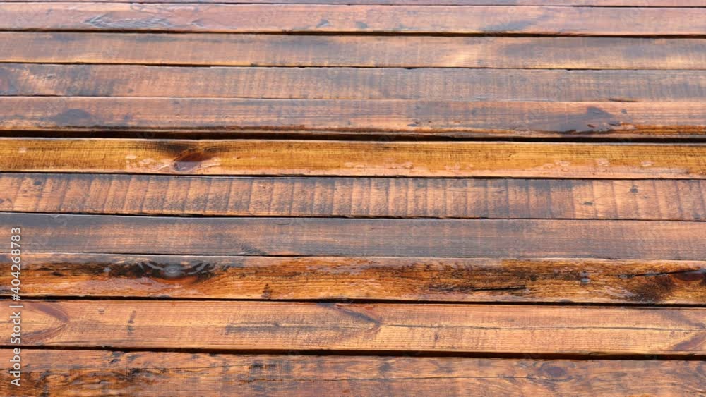 Raindrops falling down on wooden brown surface of deck outdoors. Abstract 4k video background. Raindrops falling down on wooden brown surface of deck outdoors. Abstract 4k video background.