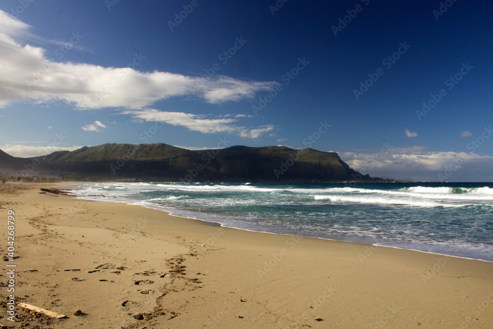 evocative image of a sandy beach with a sea of many colors and clear skies