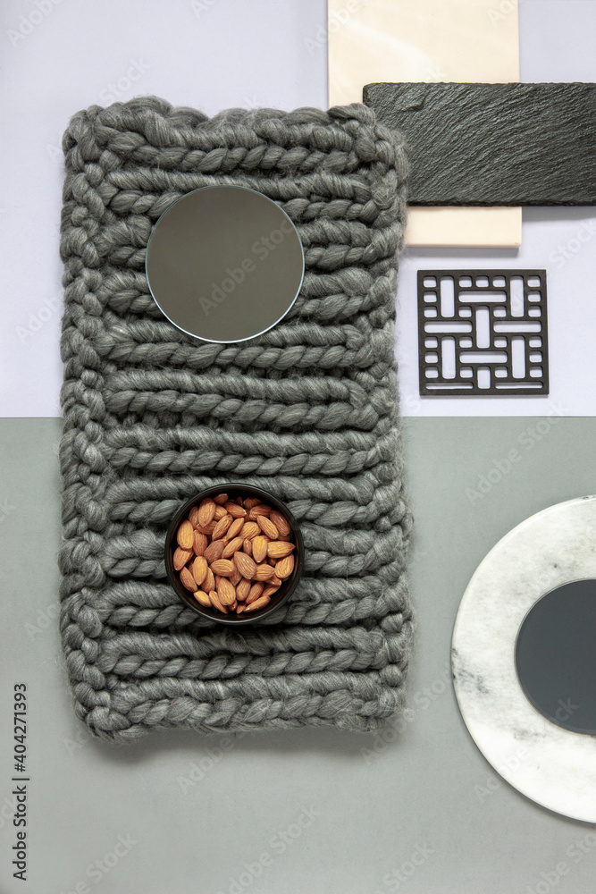 Naklejka premium Modern trendy wellness concept with almond, natural stones plates and knitting homemade. Close up, top view on neutrals tones paper background