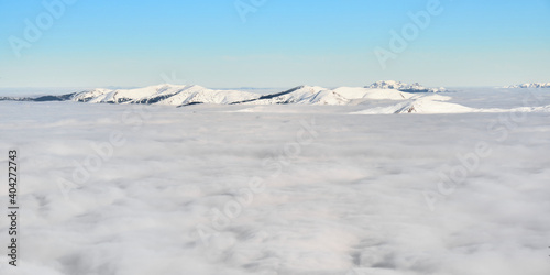 Sea of clouds in Winter, above Sinaia ski resort in Romania, with snow covered Carpathian mountain peaks in the distance. Temperature inversion, cloud inversion. 