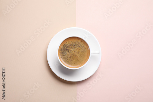 Cup of aromatic coffee on color background, top view