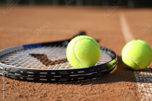 Tennis balls and racket on clay court, closeup