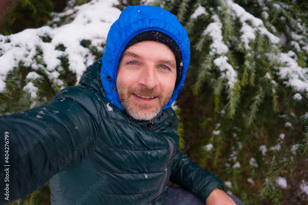 young happy and attractive tourist man taking selfie portrait with mobile phone cheerful in city park during Christmas snowfall enjoying and playing with snow young happy and attractive tourist man taking selfie portrait with mobile phone cheerful in city park during Christmas snowfall enjoying and playing with snow