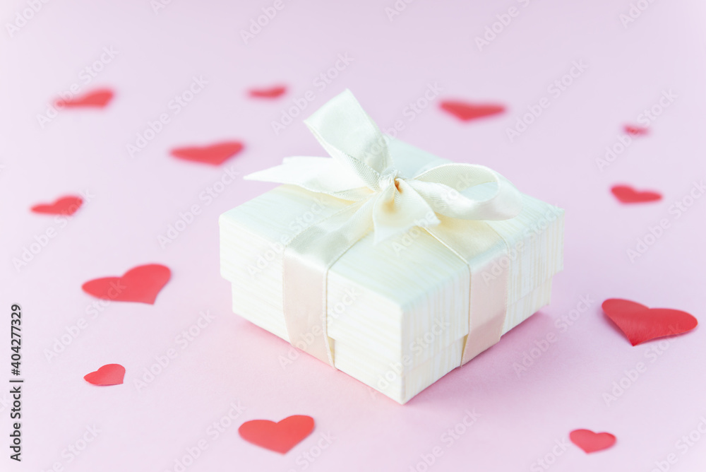 Gift box on a pink background with red hearts. Valentine's Day.