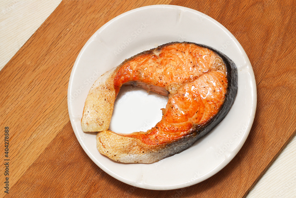 Cooked appetizing salmon steak on a snow-white plate. Cooked appetizing salmon steak on a snow-white plate.